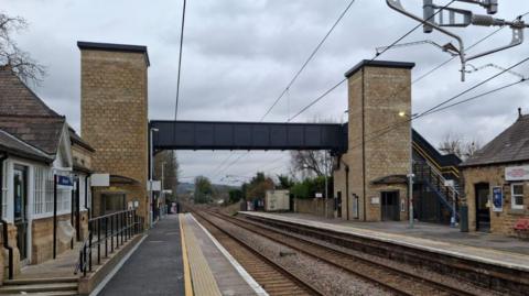 Two platforms either side of a railway line are linked by a footbridge.