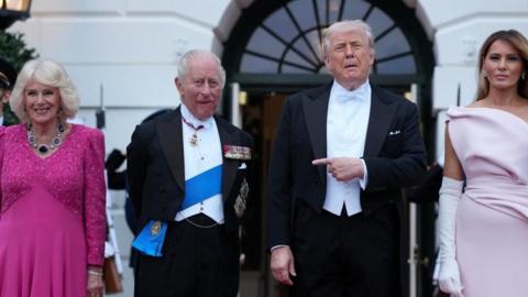 President Donald Trump points at King Charles III as they stand with First Lady Melania Trump and Queen Camilla