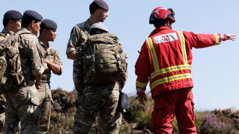 Gurkhas are seen working with firefighters