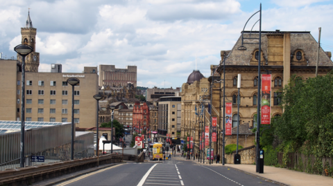 Bradford city centre showing a wide street with black posts hung with red banners