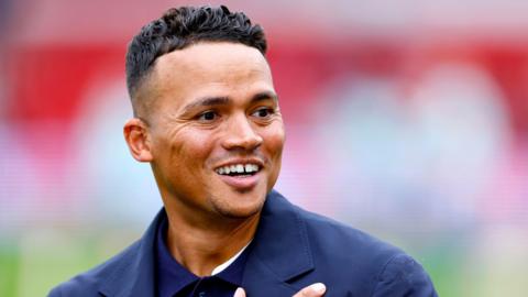 Jermaine Jenas smiling in a blue jacket