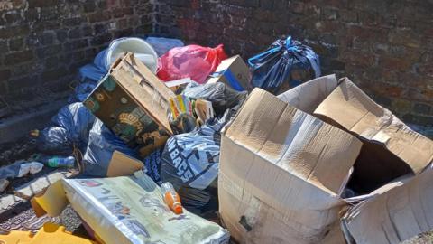 Fly-tipping including cardboard boxes, bins and empty bottles