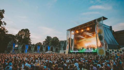 A crowd of people watch a band perform in York's Museum Gardens.