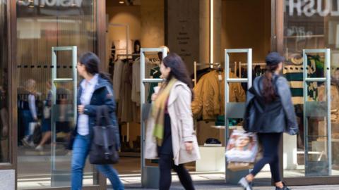 Shoppers walk past a retail clothing store