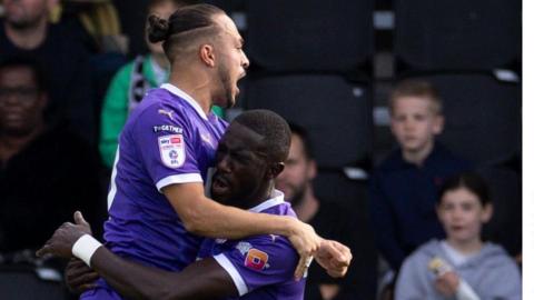 Jodi Jones leaps onto team-mate Alassana Jatta to celebrate a Notts County goal