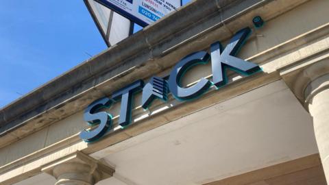 A dark blue capitalised sign on the front of the building stating 'STACK'.