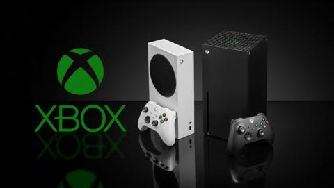 From left to right, the green Xbox logo, white Series S and black Series X consoles on a shiny reflective black surface and black backdrop. 
