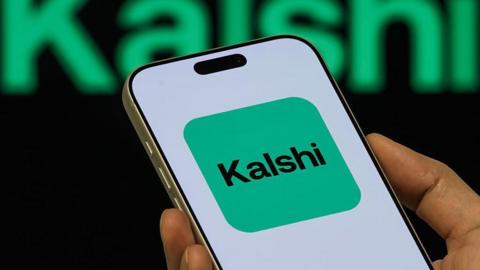 A smartphone shows the green logo for Kalshi