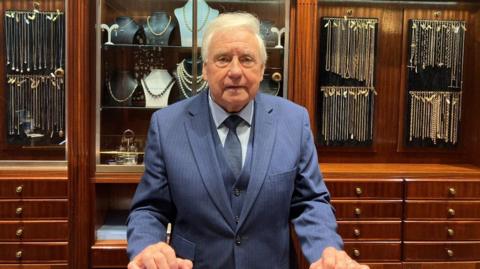 Grenville Price stood in front of a number of jewellery filled display cabinets