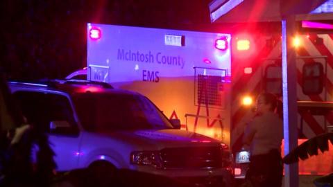 Image of two emergency vehicles outside the scene, with a woman in uniform standing by one of them