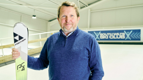 Nick Jenkins wearing a blue jumper while holding a ski inside an indoor ski slope