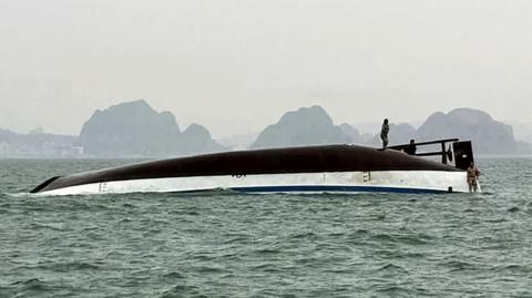 A man stands on a tourist boat that capsized in Ha Long Bay