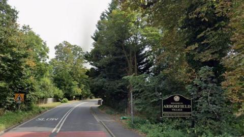Reading Road in Arborfield is a quiet road with trees on wither side, and a sign saying the village's name on the right hand side.
