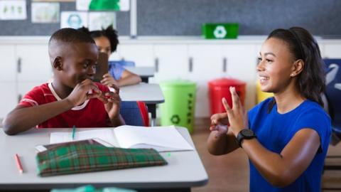 A teacher and boy communicating with each other in sign language