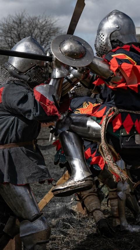 People in medieval armour fighting with swords. 