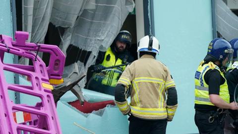 Emergency services workers inspect damage to a window at the Holiday Inn Express in Rotherham, after rioters caused disorder on 4 August