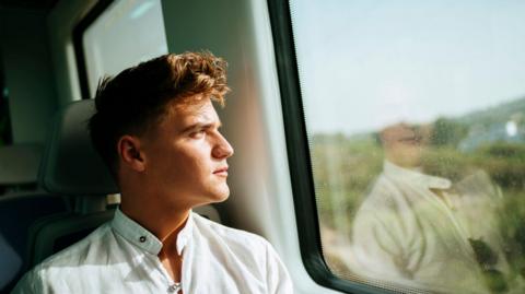 Man sits at generic train window 
