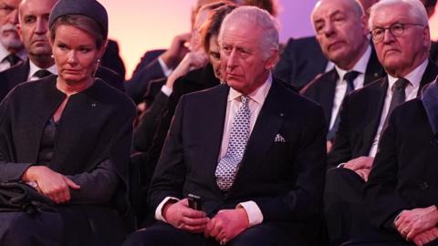 King Charles III sitting down at a service at Auschwitz-Birkenau in Poland.