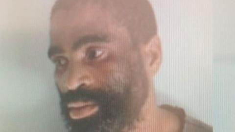 A police image of James Neo Tshoaeli, who sports a beard and looks away from the camera