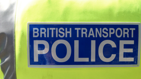 A generic photo of a yellow hi-vis. The words British Transport Police are in white letters on a blue background. 