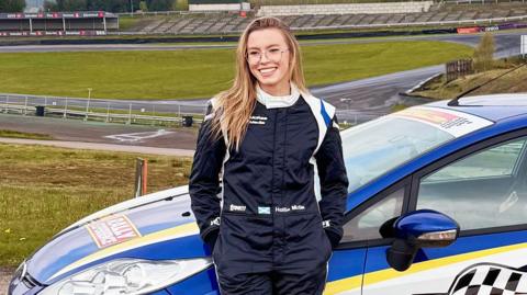 Hollie stands in front of a car at Knockhill racing circuit