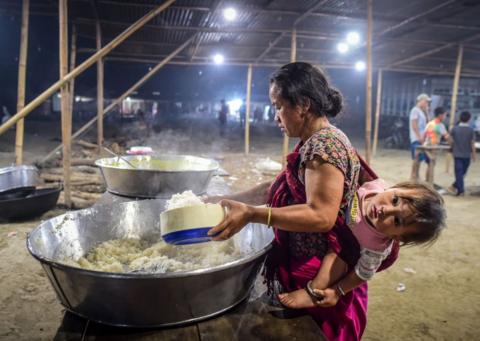 A woman from the Meitei ethnic group serves herself food at a relief camp for internally displaced people on April 27, 2024 in Imphal, Manipur, India. 