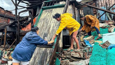 People trying dealing with debris in destroyed building in Cuba