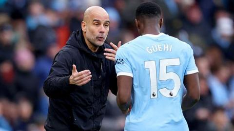 Pep Guardiola, manager of Manchester City, speaks with Marc Guehi on the touchline