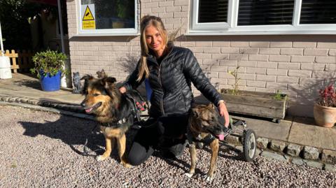 Natalia George with two of the rescued dogs - one can we seen with wheels instead of back legs