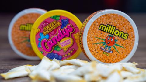 Three circular tubs of nicotine pouches being sold in packaging resembling children's sweets, called 'millions' and 'sweet nicopods candys gummy bears'.