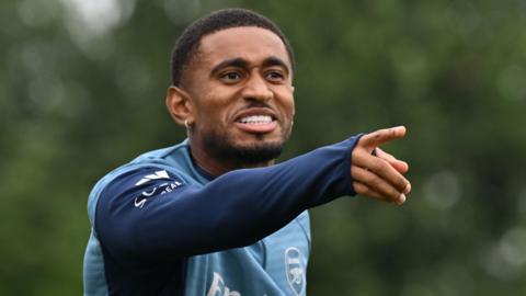 Reiss Nelson pointing with his right hand while in Arsenal kit