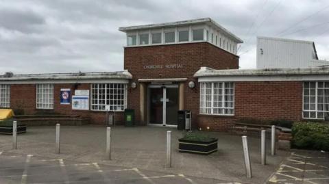 Outside the Churchill Hospital in Oxford on a cloudy day. The car park in front of the building is empty.