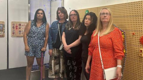 Five mothers standing in a play centre looking a the camera