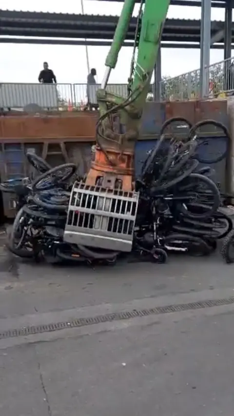A pile of bike tyres in the jaws of heavy machinery