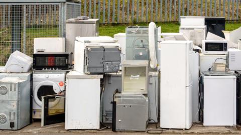 A selection of fridges and freezer piled up