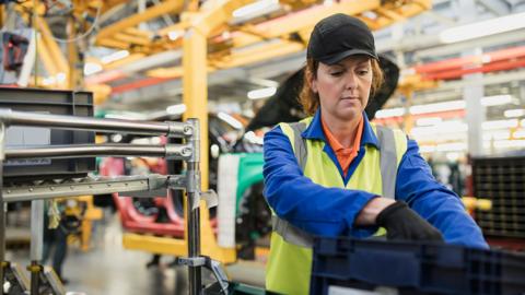 Stock photo shows a worker sorting parts in a factory in the UK