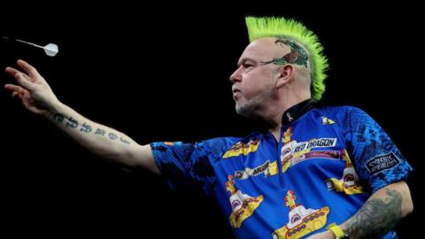 Peter Wright throws a dart while wearing a Beatles-themed shirt