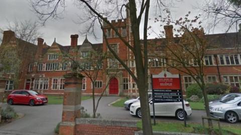 The outside of a school building with cars parked outside