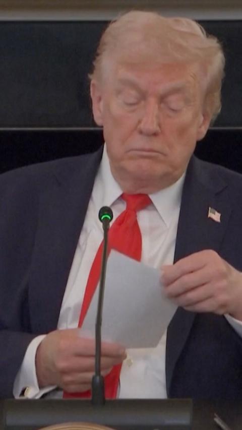 Donald Trump looks at paper note
