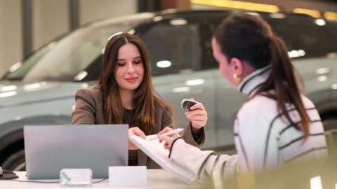 Woman speaking to saleswoman in car showroom (stock image)