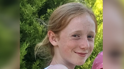 A picture of Ruth Szymankiewicz, a teenage girl who is smiling at the camera and has shoulder-length ginger hair.