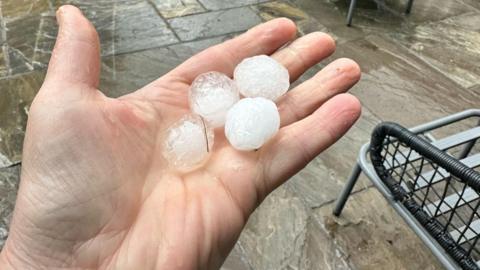 Hand holding four hailstones the size of ice cubes