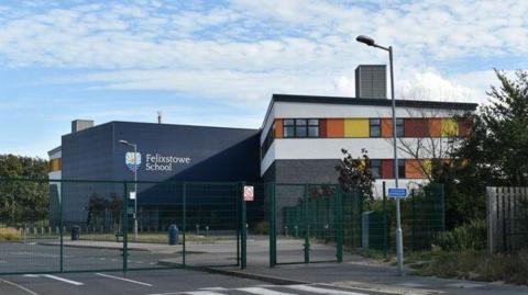 The exterior of Felixstowe School. It has block structure, with one block being dark grey the other white with coloured sections higher up.