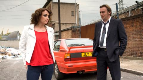 A woman and man standing in front of a car.