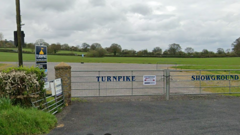 Google Street View of the gated entrance to an empty Turnpike Showground. The closed metal gates bear the name of the venue.