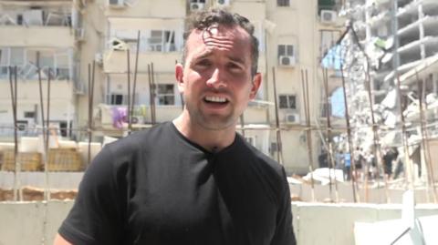 Hugo Bachega in front of a damaged building in Israel's Bat Yam
