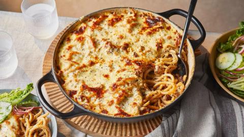 A large casserole dish filled with spaghetti layered with melted cheese.