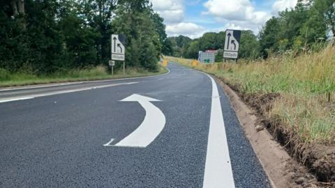 A road with is visible with white markings painted on it. 