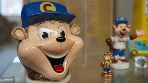 Memorabilia including the monkey from the Coco Pops box in a cabinet.