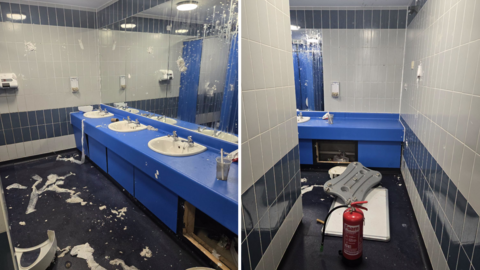 The inside of a public toilet block, there is vandalism of a baby changing table, soap dispensers with wet toilet rolls stuck to walls and mirrors and the floor.